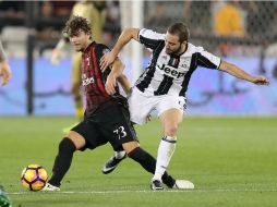Romagnoli (I), del Milan, disputa un balón con Higuaín (D), de Juventus. AFP / K. Jaafar