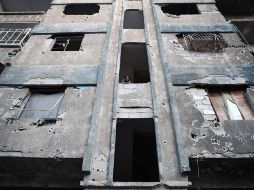 Una niña ve a través de la ventana de uno de los edificios dañados. AFP / A. Doumany