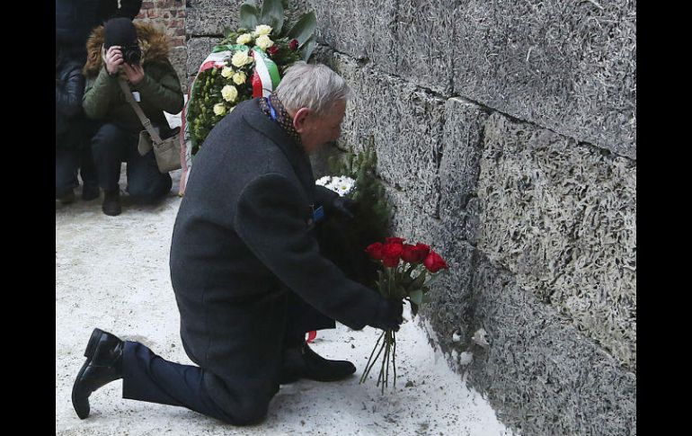 Un sobreviviente coloca una ofrenda en el muro de ejecución del antiguo campo de exterminio nazi. AP / C. Sokolowski