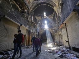Chicos de Alepo caminan en una calle dañada por las acciones bélicas. AFP / L. Beshara
