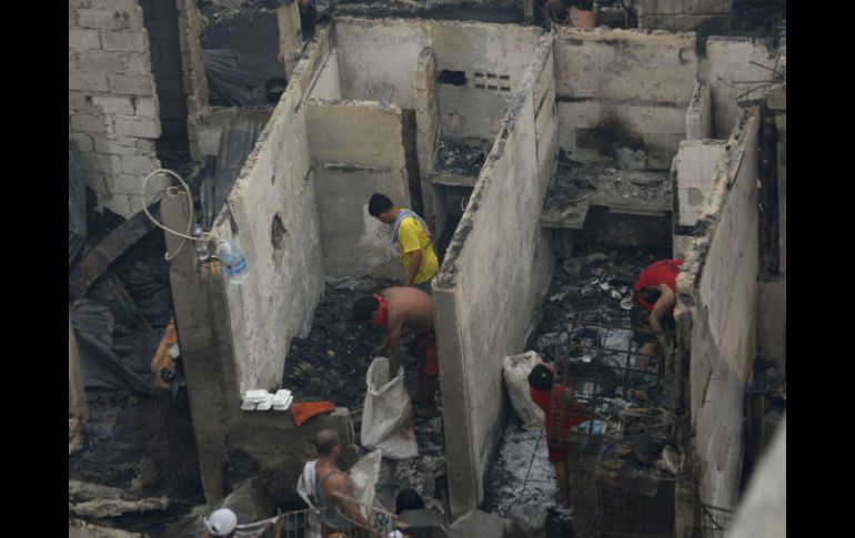 Varias personas tratan de rescatar algunas de sus pertenencias entre los restos carbonizados. AFP / T. Aljibe