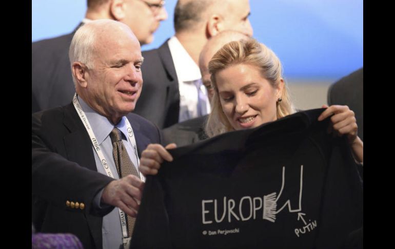 McCain sonríe al recibir una camiseta de la periodista y política Svitlana Zalishchuk, en la Conferencia sobre Seguridad. AP /