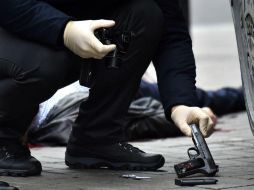 Un oficial ucraniano recoge un arma de fuego en la escena del crimen para su análisis. AFP / S. Supinsky