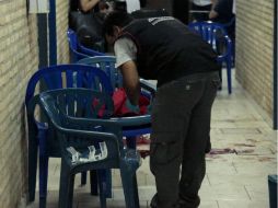 Un miembro de la Policía científica recoge muestras de sangre en el lugar donde el joven opositor murió. EFE / A. Peña