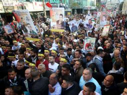 Palestinos sostienen imágenes de sus familiares presos en cárceles israelíes durante una manifestación. ESPECIAL / Xinhua