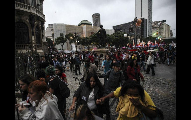 Manifestantes corren de gases lacrimógenos lanzados por la policía durante protestas en la huelga general convocada. EFE / A. Lacerda