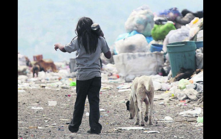 Una menor con su perro caminan rumbo a su casa entre montañas de basura en el vertedero municipal del Bordo de Xochiaca. EFE /