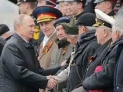Vladímir Putin (i), estrecha la mano a varios veteranos de la II Guerra Mundial durante el desfile militar por el Día de la Victoria. EFE / Y. Kochetkov