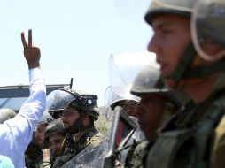 Un manifestante hace el gesto de la victoria ante soldados israelíes durante una protesta para apoyar a los presos. EFE / A. Badarneh
