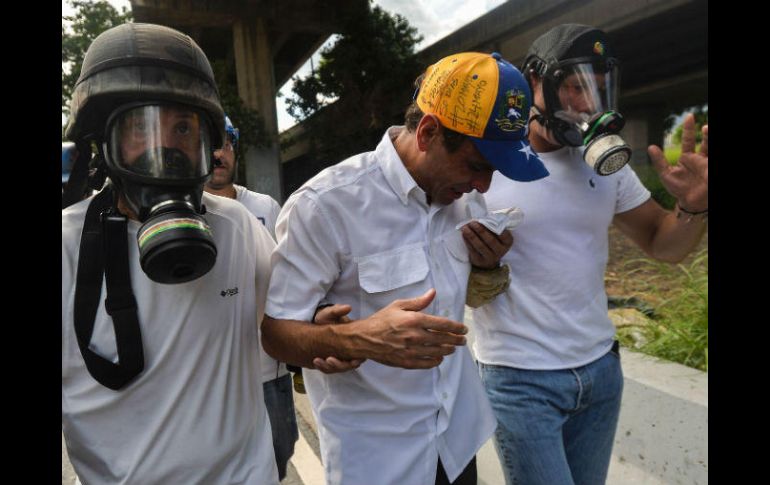 Capriles tuvo que ser auxiliado por sus guardaespaldas para salir del lugar. AFP / L. Robayo