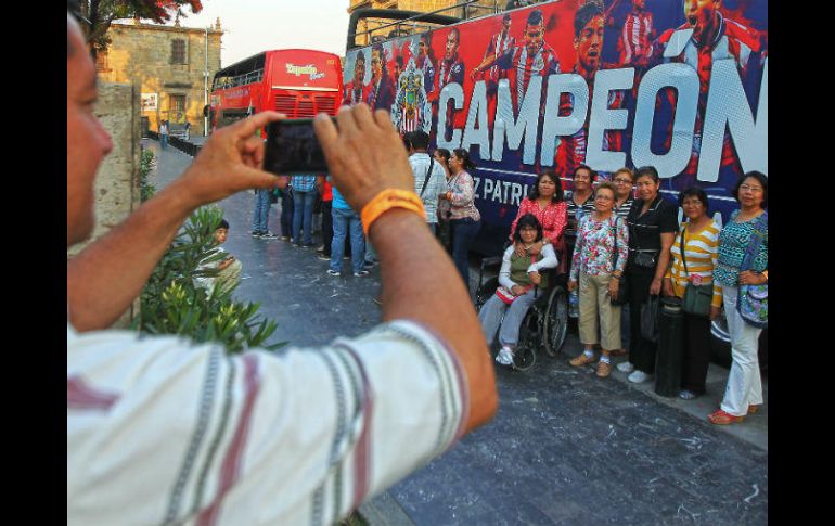 Varios turistas quisieron fotografiarse frente a uno de los autobuses que ayer transportó a los jugadores de las Chivas. EL INFORMADOR / E. Barrera