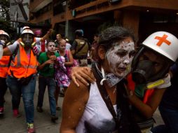 Miembros de la Cruz Roja socorren a los afectados por los gases lacrimógenos durante una protesta opositora. EFE / M. Gutiérrez