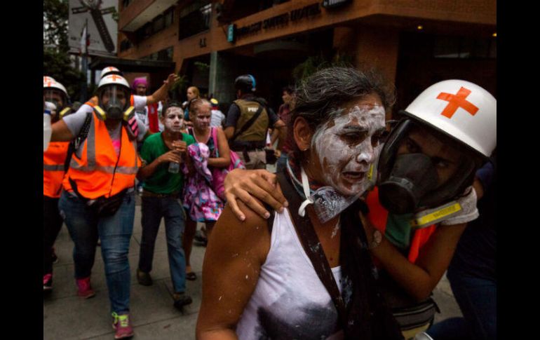 Miembros de la Cruz Roja socorren a los afectados por los gases lacrimógenos durante una protesta opositora. EFE / M. Gutiérrez