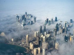 Vista aérea de varios edificios emergiendo a través de la niebla que cubre el horizonte de Doha, en Qatar. EFE / O. Valat