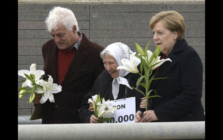 Jarach, con un letrero de “Son 30 mil”, caminó tomada del brazo de una atenta Angela Merkel en el Parque de la Memoria. AFP / J. Mabromata