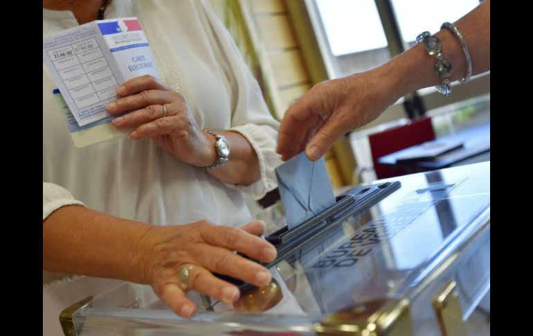 Una mujer deposita su papeleta electoral en un centro de Vertou. AFP / L. Venance