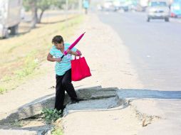Senderos de tierra. Una mujer batalla para alejarse del Periférico, situación común para peatones que descienden de vehículos. EL INFORMADOR / G. Gallo