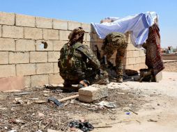 Soldados revisan sus armas tras un muro durante los enfrentamientos entre el Estado Islámico y las FSD. EFE / Y. Rabie