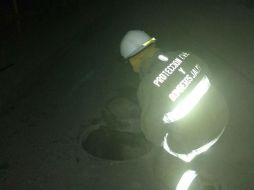 Un bombero destapa una de las alcantarillas para confirmar la fuga de combustible. ESPECIAL /