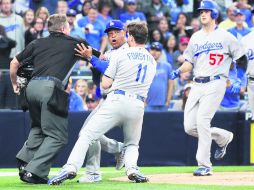El mánager de los Dodgers, Dave Roberts (c), es retenido por el tercera base Logan Forsythe (#11) y el árbitro Greg Gibson (i). AP /