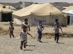 Varios niños juegan con molinillos de viento caseros en el campamento de desplazados de Hasan Sham. EFE / J. Fuentelsaz