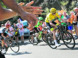 El británico Chris Froome (suéter amarillo) y un grupo de ciclistas son alentados por los aficionados. AP /