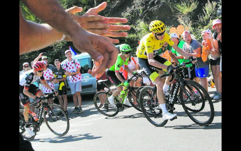 El británico Chris Froome (suéter amarillo) y un grupo de ciclistas son alentados por los aficionados. AP /