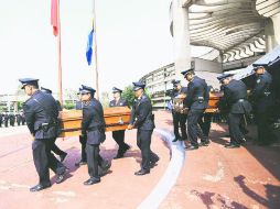 Compañeros de los efectivos caídos trasladan los restos a la explanada del Edificio Central, donde se dio el último pase de lista. ESPECIAL /