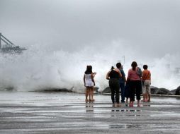 Varias personas observan el alto oleaje en costas de Veracruz. SUN /