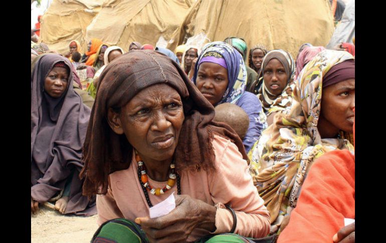 Varias personas esperan a que voluntarios les brinden una ración de comida en un campo de refugiados. AFP / ARCHIVO