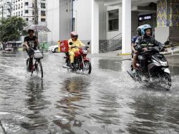 Motociclistas circulan por una calle inundada en Makati, donde el tifón 'Hato' causó considerables daños. EFE / R. Cristino