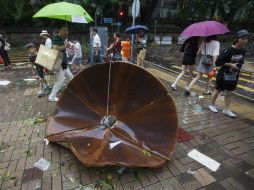 Varios viandantes pasan junto a un plato de un satélite que voló de un tejado por el paso del tifón 'Hato' en Hong Kong. EFE / A. Hofford