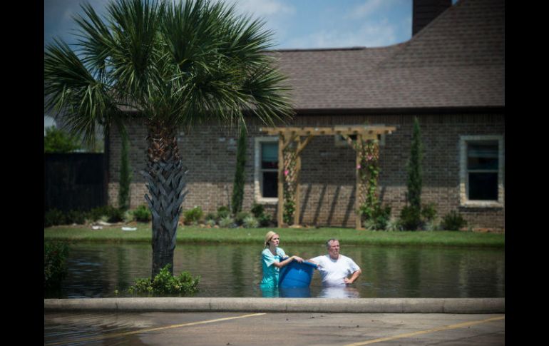 Una mujer y un hombre transportan en una cubeta de plástico algunas de sus pertenencias. AFP / E. Kask