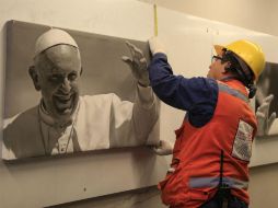 Un hombre cuelga unas fotografías del Papa Francisco en uno de los pasajes subterráneos del centro de Bogotá. EFE / R. Maldonado