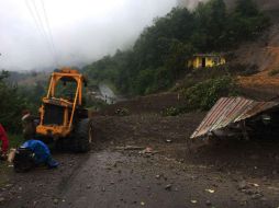 Unos trabajadores usan maquinaria para abrir el camino bloqueado por un deslizamiento de tierra provocado por el paso de la tormenta. EFE / L. Monroy