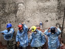 Rescatistas se colocan impermeables para seguir con la búsqueda de sobrevivientes. AFP/R. Schemidt
