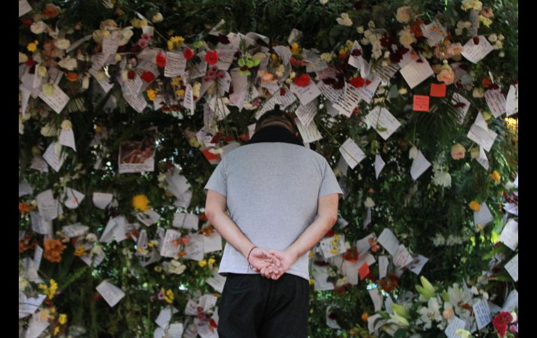 Un hombre observa varios arreglos florales dejados en un improvisado altar en memoria de las víctimas del terremoto.