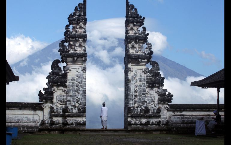 KARANGASEM, INDONESIA.- Un habitante observa el volcán Agung desde un templo. Las autoridades ordenaron evacuar las aldeas en una zona de peligro 12 kilómetros a la redonda del cráter. AP/F. Lisnawati
