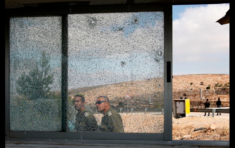 HAR ADAR, CISJORDANIA.- Integrantes de las fuerzas de seguridad israelíes pasan una ventana rota a la entrada de un asentamiento, luego de que un palestino abriera fuego contra personal de seguridad. AFP/M. Kahana
