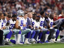 Sin dejar de sujetar los brazos, los Vaqueros se pusieron de pie cuando la bandera de Estados Unidos se desplegó en el terreno. AFP / C. Petersen