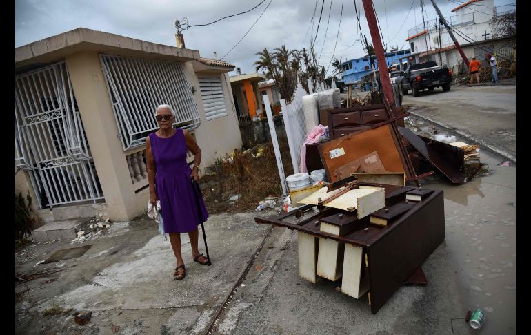 Una habitante de Puerto Rico junto a los daños ocasionados en su hogar.