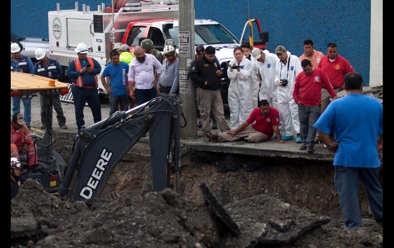 Bomberos y elementos de Protección Civil recuperan el vehículo que cayó en el socavón, en el cual viajaban cinco personas. EFE