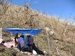 Ante la falta de recursos y espacios, las personas han tenido que improvisar; en la imagen, una familia toma una ducha al aire libre con una lona como protección. AFP/H. Retamal