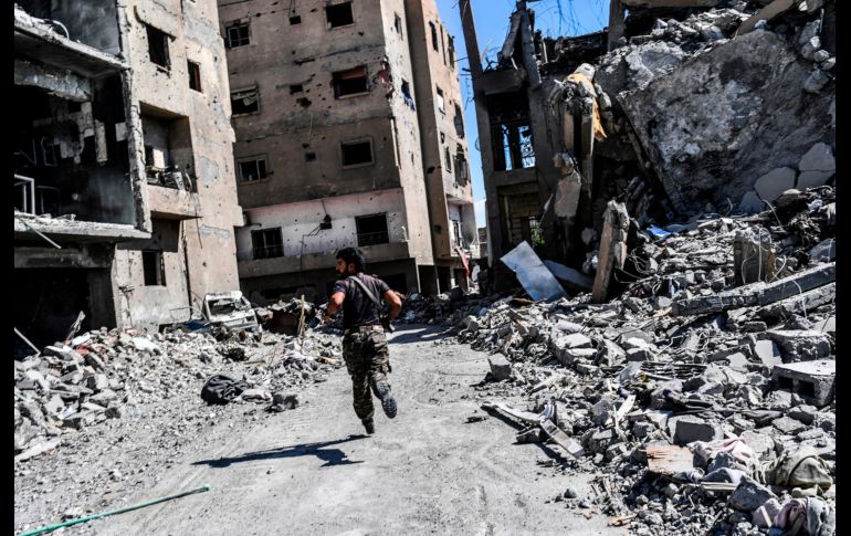 Un integrante de las Fuerzas Democráticas Sirias corre para tomar una posición cerca de un hospital en Raqa, durante la ofensiva contra los yihadistas del Estado Islámico. AFP/B. Kilic