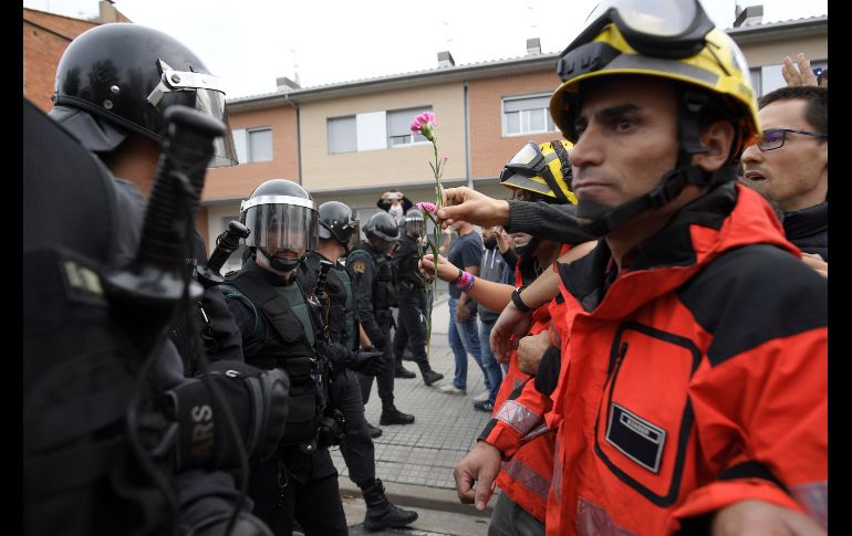 Una persona le da un clavel a oficiales de la Guardia Civil. El Ministerio español del Interior indicó que 19 policías y 14 guardias civiles también resultaron heridos al intervenir para retirar urnas.