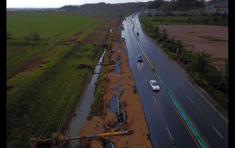 Autos transitan por una autopista junto a postes de electricidad caídos por el paso del huracán 