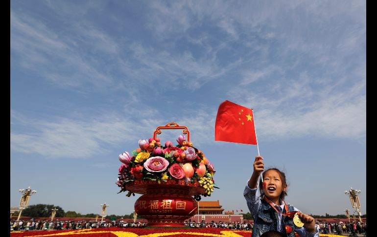 Una niña se sienta sobre los hombros de su padre junto a una canasta con réplicas de flores y frutas en la plaza Tiananmen, en Pekín. AP/A. Wong