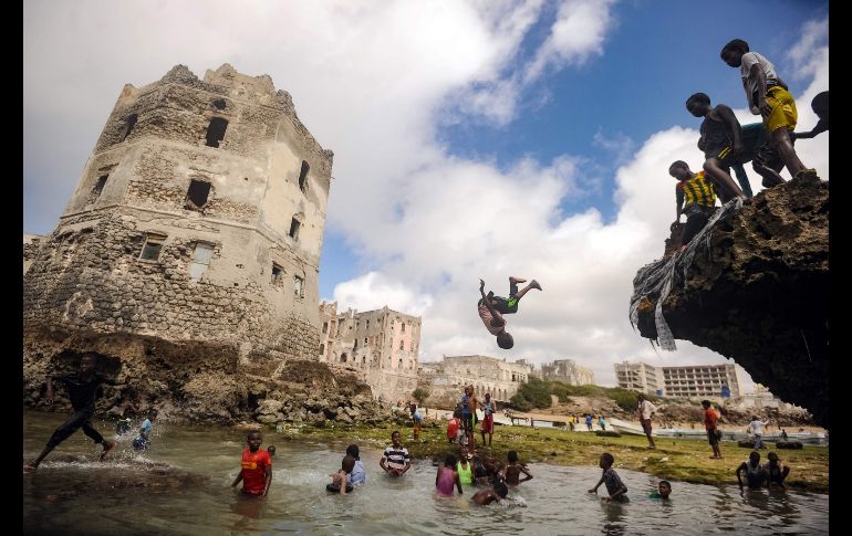 Niños juegan y nadan frente a las ruinas de un edificio antiguo junto al mar en Mogadiscio, Somalia. AFP/M. Abdiwahab