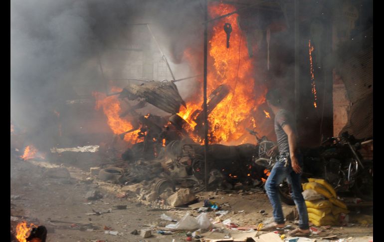 Un sirio observa un puesto en llamas tras un ataque aéreo sobre un mercado de vegetales en Maaret al-Numan. AFP/M. Al-Bakour