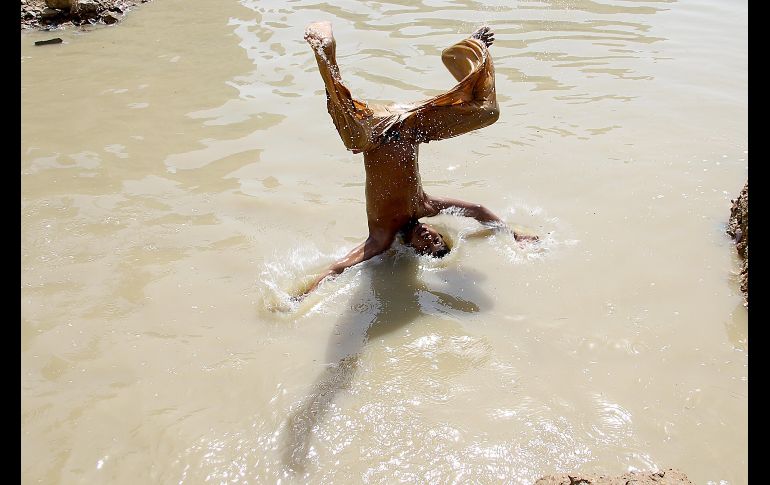 Un niño se refresca en un estanque en Karachi, Pakistán. EFE/S. Akber